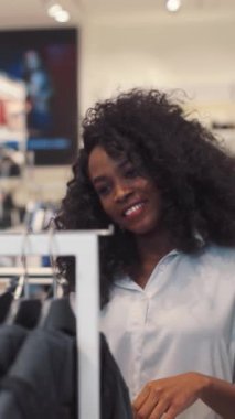 Sevimli kıvırcık saçlı neşeli genç bir kadın alışveriş merkezinde etkileşim halindeyken mutluluk saçar.