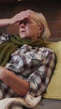 Yaşlı bir kadın, sıcacık bir battaniyeye sarılmış, sıcaklığı ve nostaljiyi somutlaştırırken düşünceli bir şekilde bakar..