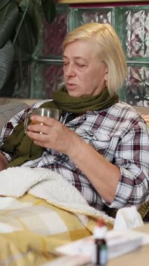 Güzel sarı saçlı yaşlı kadın akıllı telefon ekranına bakıyor, daktilo ediyor. Yatakta yatan, kızıyla mesajlaşan, çay içen yaşlı kadının portresi. İçeride. Yakın plan..