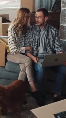 Bir erkek ve bir kadın rahat bir şekilde kanepede oturuyor, her ikisi de dizlerine yerleştirilmiş bir dizüstü bilgisayara bakmaya odaklanmış.