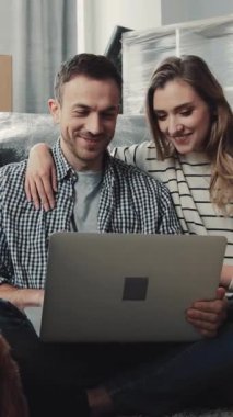 Bir erkek ve kadın dizüstü bilgisayarda samimi bir anı paylaşıyorlar, önce bir kanepede, sonra yerde, birlikte gülüyor ve fikirlere odaklanıyorlar.