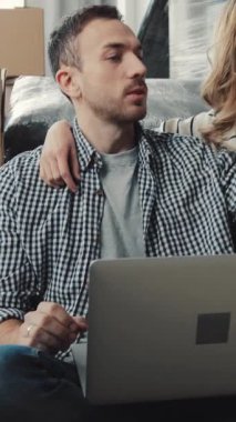 Kanepede dizüstü bilgisayar kullanan bir çiftin olduğu rahat bir oturma odası sahnesi ve yerdeki oyuncu köpekleri arkadaşlıklarını ve rahatlamalarını ön plana çıkarıyor.