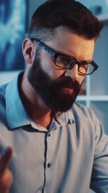 Bu ilgi çekici videoda, mavi gömlekli ve gözlüklü bir adam masasından görüşlerini paylaşıyor ve sıcak, sofistike bir atmosfer yaratıyor.