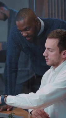 Çağdaş bir ofis ortamında, iki deneyimli profesyonel bir dizüstü bilgisayarla yapıcı bir tartışmaya girişirler.