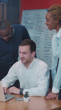 Bir grup profesyonel, canlı bir ofis ortamında dizüstü bilgisayar kullanırken bir masada birlikte çalışıyorlar.