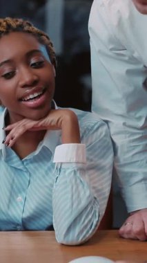 Genç bir kadın sevinçle gülümsüyor, aktif olarak verimli bir toplantıya katılıyor, takım çalışması ve işbirliği sergiliyor.