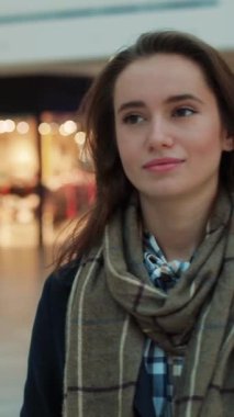 Şık bir genç kadın, şehir arka planına karşı rahat bir eşarp eşliğinde ekose bir gömlek giyerken görülebilir.