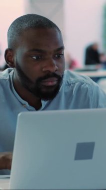 Kendini işine adamış ve profesyonel bir birey, modern ve açık bir çalışma alanında bir dizüstü bilgisayar kullanarak aktif olarak çalışıyor.