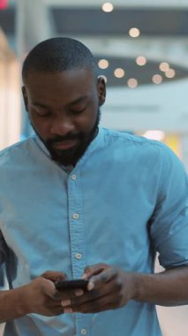 Modern ve çağdaş bir ortamda akıllı telefonuna özenle odaklanan bir adam, günümüzün dijital yaşam tarzını yansıtıyor.