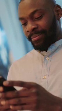 Çevresinde çağdaş ve modern bir ortamın tadını çıkarırken akıllı telefonuyla gülümseyen bir adam.