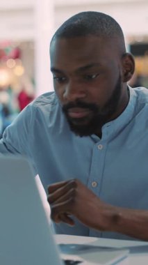 Canlı ve canlı bir kafe ortamında dizüstü bilgisayarına derinden odaklanmış bir adam olağanüstü üretkenliğini sergiliyor.