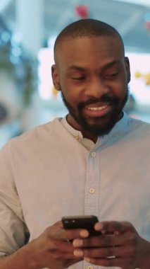 Neşeli ve neşeli bir adam bugün akıllı telefonuyla canlı, canlı ve modern bir ortamda meşgul.