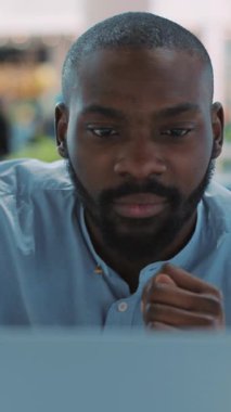 Odaklanmış ve kararlı bir adam modern çalışma ortamında laptopuyla aktif olarak meşgul.