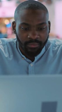 Bir adam yoğun bir şekilde bilgisayar ekranına odaklanmış modern, çağdaş bir ortamda üretkenliği somutlaştırıyor.