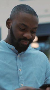 Son derece odaklanmış bir adam, çağdaş kentsel bir ortamda bulunduğu sırada akıllı telefonuyla yoğun bir şekilde meşgul oluyor.