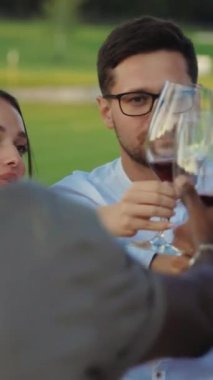 Neşeli ve keyifli bir açık hava buluşması. Dostlar kadehlerini şaklatarak neşeli bir kutlama yapıyorlar.