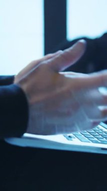 Odaklanmış bir profesyonel, devam eden siber güvenlik girişimlerini ön plana çıkaran, modern teknoloji ortamında bir dizüstü bilgisayarda yazı yazıyor.