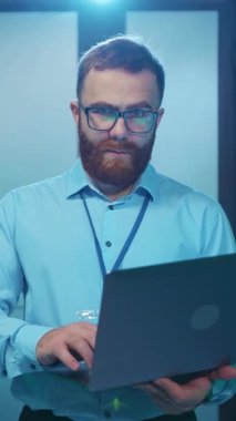 Kendini işine adamış ve odaklanmış bir profesyonel adam modern ofis ortamında özenle bir dizüstü bilgisayar üzerinde çalışıyor.