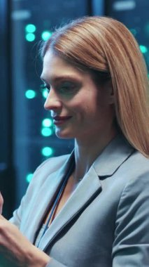 Gösterişli bir takım elbise giymiş özgüvenli ve başarılı bir profesyonel yüksek teknoloji arkaplanının ortasında dikiliyor.