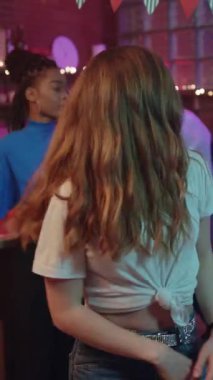 Genç bir kadın neşe içinde dans ederken ve eğlenceli bir sosyal toplanma havası sergilerken, hayat dolu bir atmosfer alanı dolduruyor.