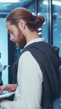 Akıllı günlük kıyafetler giymiş profesyonel bir adam, teknik bir ofis içinde tamamen işine odaklanmıştır.