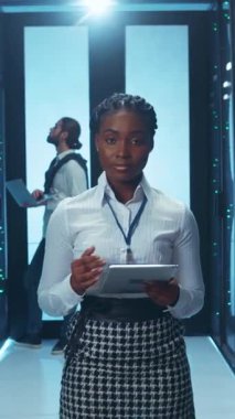 Kendini işine adamış ve yetenekli profesyonel bir kadın çağdaş bir veri merkezinde tablet üzerinde özenle çalışıyor.