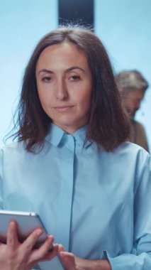 Bir kadın dikkatle akıllı telefonuna bakıyor, modern teknolojiye dalmış, canlı çağdaş bir ortamda.