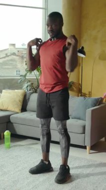 Formda ve sağlıklı bir adam şık ve modern bir ev ortamında detaylı bir çalışma rutini sergiliyor.