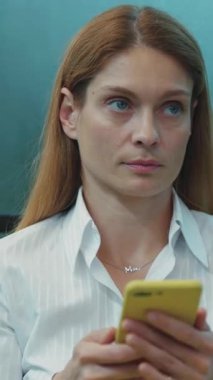 Kendini adamış profesyonel bir kadın, çağdaş bir kentsel ortamda akıllı telefonuna yoğun bir şekilde konsantre oluyor.