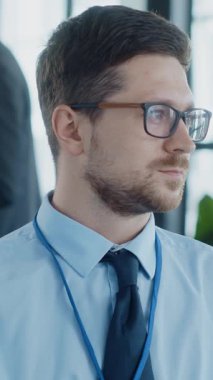 Şık gözlük takan odaklanmış bir işadamı, çağdaş bir ofis ortamında özenle çalışıyor.