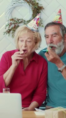 Parti şapkaları ve dijital cihazla kutlama yapan neşeli yaşlı bir çift özel bir anı yakalıyor..