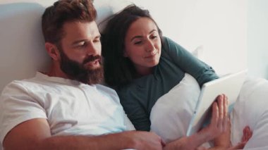 Sevimli evli çift yatakta yatar, internette yorumları, tablet ekrandaki bilgileri tartışırlar. Birkaç gol, ortaklık, vlog yazarları. Takipçiler, sosyal ağlar.