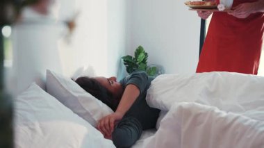 Sevimli esmer kadın, kırmızı önlüklü sempatik sakallı sevgilisi tarafından yatakta servis edilen kahve aromasından uyanır. Romantik atmosfer, gerçek aşk, flört. Birlikte mutluyuz.