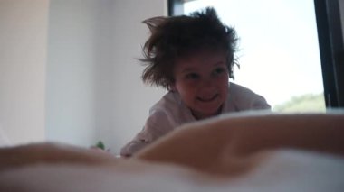 Sevimli, komik küçük çocuk yatakta deliriyor. Oynamak, eğlenmek, duygular. Eğlenceli, neşeli bir ruh hali. Mutlu çocukluk.