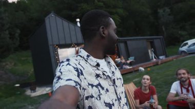 Neşeli çok ırklı arkadaş grubu kokteyllerini kaldırır ve fotoğrafın ortasında gülümseyen Afro-Amerikalı bir adamla selfie çekerler. Parti fotoğrafları, takılmalar, takılmalar..