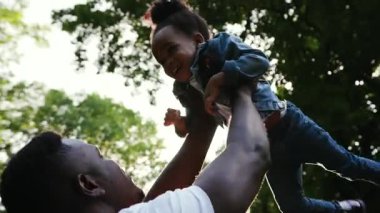 Yaklaş Afrikalı baba. Kızına sarılıp el ele tutuşuyor. Tatili parkta birlikte geçiriyorlar.