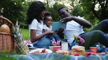 NEW YORK - 5 Nisan 2017: Parkta kızı olan tatlı Afro-Amerikan çift, piknik yapan genç erkek ve çocuk.