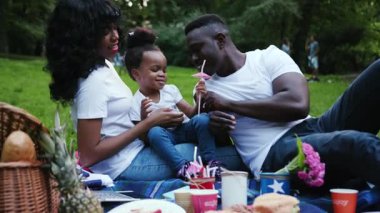 Kızı olan Afrikalı Amerikalı çifti şehir parkında piknik yapan genç bir erkek ve çocuk. Dışarıda eğleniyorlar. Yavaş çekimde gülüyorlar.