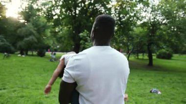 Afrikalı bir babanın kızına sarılıp el ele tutuşması tatilini parkta birlikte geçirmesi aile şefkati mutlu yavaş çekim aşk çocuğu yaz çocuğu çocuk doğa kızı anne baba