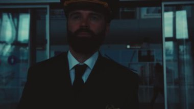 Yakışıklı mavi gözlü, sakallı beyaz pilot havaalanı terminalinden çıkıyor. Kendine güven, erkeklerin gücü, gaddarlık. Meslek konsepti. Erkek portresi