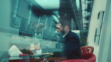 Güzel sakallı pilotun havaalanı kafeteryasında oturup sütlü kahve içişini yakından izleyin. Beklemek, kahve molası, dinlenmek. Erkek portresi