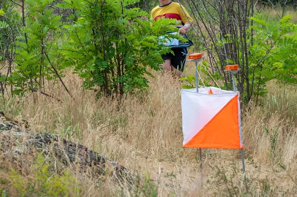 Orienteering. Check point Prism and composter for orienteering. The athlete is approaching the control point
