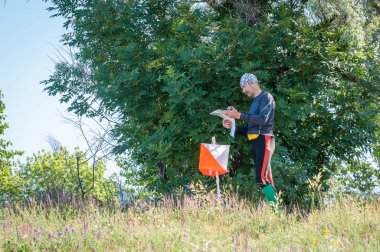 Yuzhnoukrainsk, Ukrayna - 26 Mayıs 2018: Orienteering yarışı. Yıllık orienteering oyun Partizan kıvılcım Kupası 2018. Denetim noktası yakınındaki atlet harita, nerede daha fazla çalıştırmak için belirleme inceliyor
