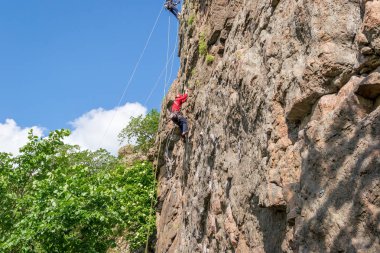Kaya tırmanışı. Genç dağcı bir dikey granit kaya tırmanıyor. Aşırı spor