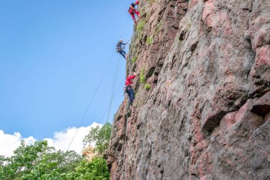 Yuzhnoukrainsk, Ukrayna - 19 Haziran 2018: dağcılık. Bir grup genç kaya dağcılar dikey granit kayaya tırmanmak. Aşırı spor. Eğitim dağcıların