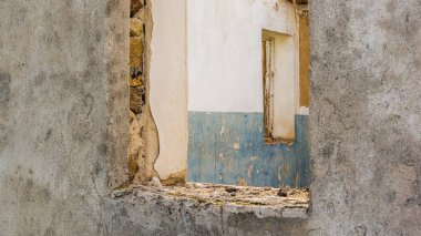 Çatı olmadan eski bir toprak evin kalıntıları. Pencereler ve kapılar yerinde duvarda delikler.