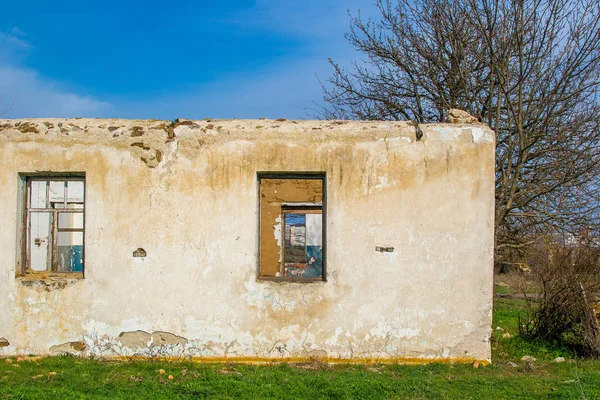 The ruins of an old earthen house without a roof. Holes in the wall at the site of windows and doors.