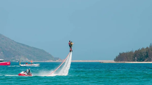 Hainan, Sanya, China - 14 de maio de 2019: Flyboarding. Voando sobre a água no tabuleiro com um poderoso jato de água. Atracção na praia. Desporto extremo e recreação . — Fotografia de Stock