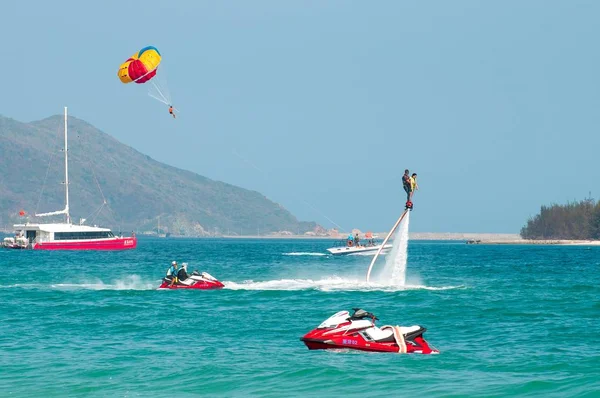 Hainan, Sanya, China - 14 de mayo de 2019: Flyboarding. Volando sobre el agua en el tablero con un potente chorro de agua. Atracción en la playa. Deportes extremos y recreación . — Foto de Stock