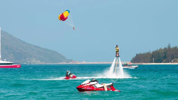 Hainan, Sanya, China - 14 de mayo de 2019: Flyboarding. Volando sobre el agua en el tablero con un potente chorro de agua. Atracción en la playa. Deportes extremos y recreación . — Foto de Stock